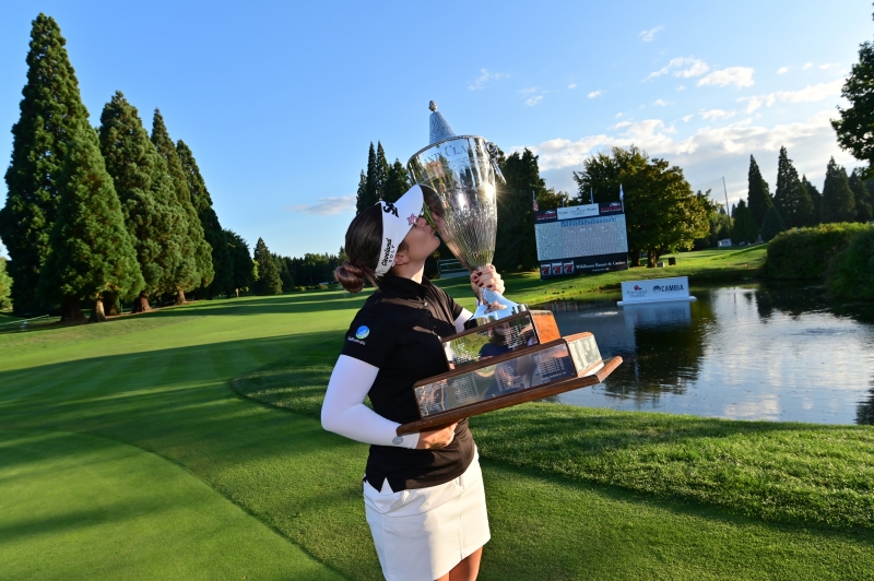 A woman holding a trophy on a gold course