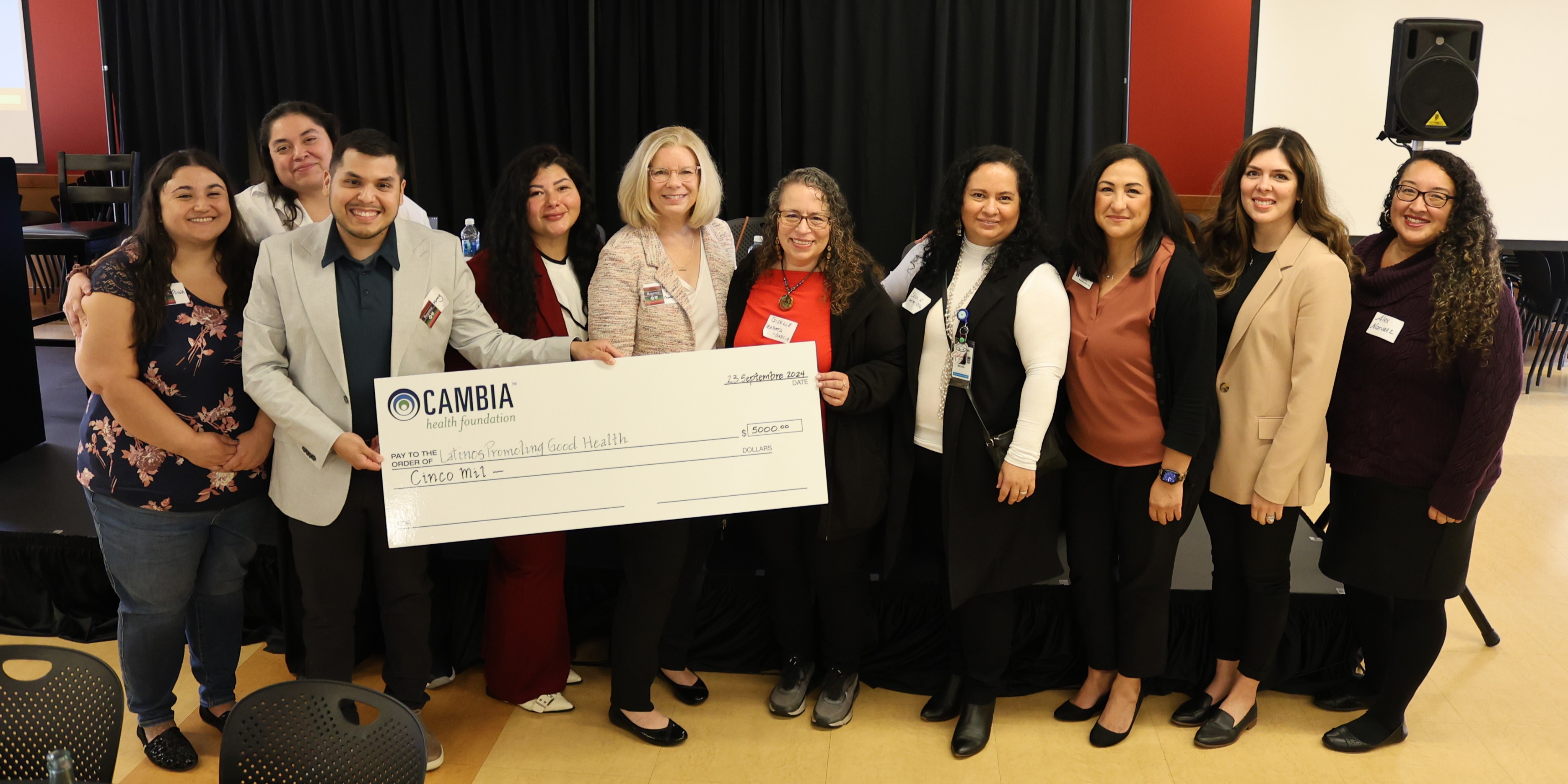 Group of attendees and panelist holding donation check