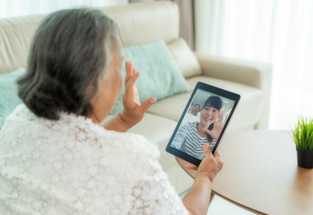 Elderly woman uses tablet to video chat 