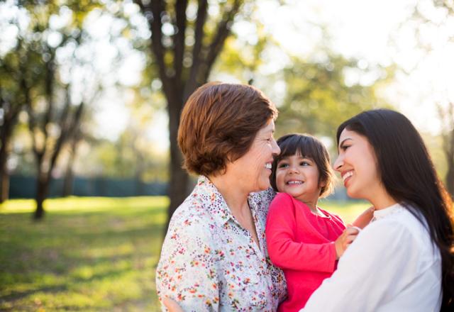 Grandmother, mother and daughter embracing and smiling in a park