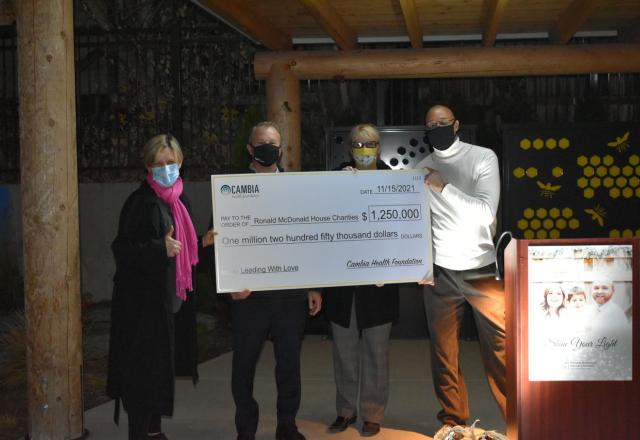 Four people holding large donation check