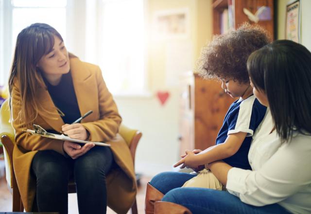 Therapist talking to young kid sitting on mom's lap