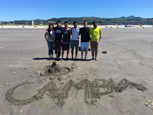 group photo on beach with cambia drawn into sand
